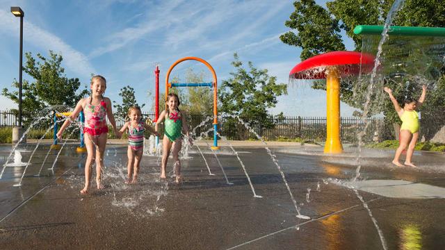 group of young girls playing in spray garden water fountains
